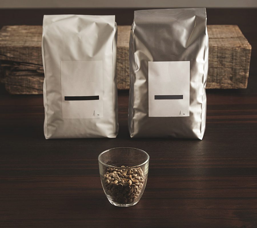 _0001_two-big-hermetic-packages-with-blank-labels-near-transparent-glass-with-raw-sampled-coffee-beans